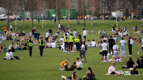 PA Media Police officers overlook people enjoying the warm weather at the Forest Recreation Ground in Nottingham.