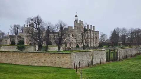 Rhian Williams Side view of stone-built stately home with wall around the outside