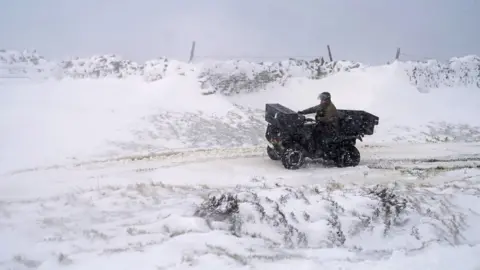 Owen Humphreys/PA A man rides a quad bike through Allenheads, Northumberland.