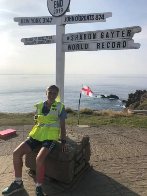 Izzy Wilkinson Sharon Gayter under the Land's End location sign