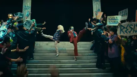 Warner Bros Lady Gaga and Joaquin Phoenix dancing on courtroom steps in Joker 2