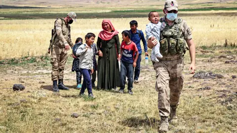 Getty Images Turkish security forces patrolling the border with Iran help an exhausted Afghan family - 6 August 2021