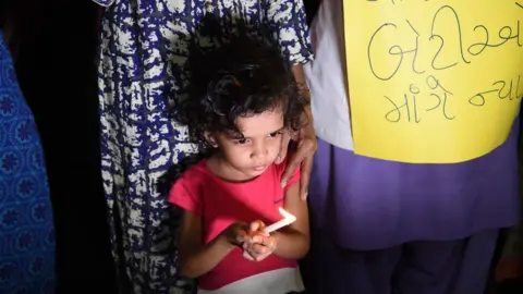 Getty Images A little girl holds a candle during a candlelight protest in India following high profile rape cases.