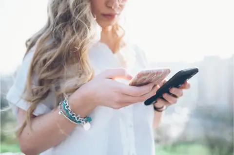 Getty Images woman with two phones