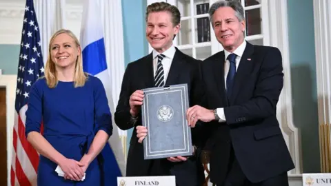 Getty Images Finnish Foreign Minister Elina Valtonen and Defence Minister Antti Hakkanen with US Secretary of State Antony Blinken pose for a photo after signing an agreement