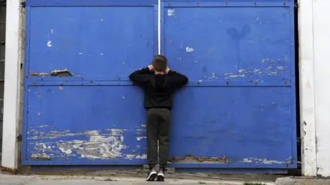 Getty Images Young fan peers through a gate at Kenilworth Road