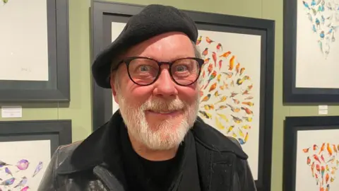 BBC Jim Moir in front of his art works