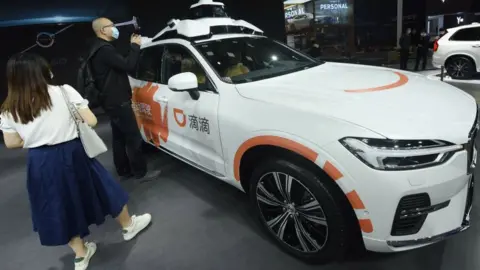 Getty Images Visitors look at Didi's new generation of driverless cars at the Shanghai Auto Show in Shanghai, China.