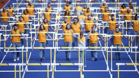 Reuters General view of the volunteers moving the hurdles for the men and women's races