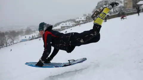 Getty Images A man leaping onto a toboggan