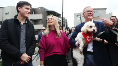 Getty Images Labor leader Anthony Albanese holds dog Toto while campaigning beside son and partner in Sydney