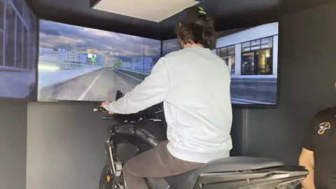 BBC A rider using the motorbike simulator