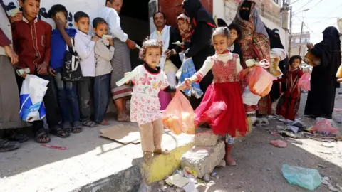 EPA Yemeni children receive free food rations from a charity in Sanaa (14 September 2018)