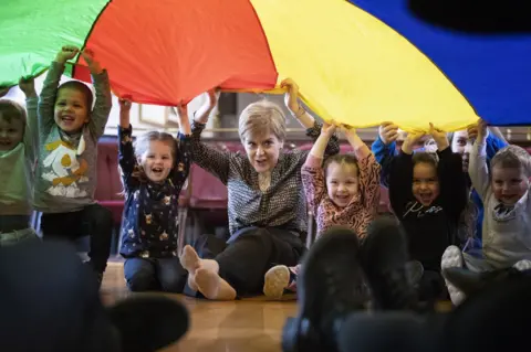 Jane Barlow / PA Media Nicola Sturgeon joins in with playtime at a nursery in Gilmerton, Edinburgh