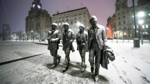 PA Media Snow falls on the Beatles Statue at Pier Head, Liverpool