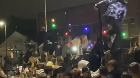 Martin Booth Fans climbing over a wall