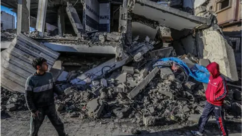 Getty Images Boys stand in front of the rubble of a building in Rafah in the Gaza Strip