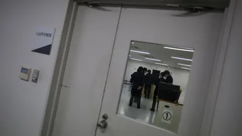 Reuters Guards seen through the window of a door at the East Japan Immigration Centre