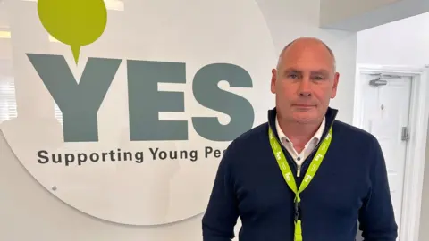 Qays Najm/BBC YES CEO Dr David Sollis in front of logo