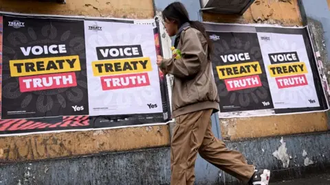 Getty Images A woman walks past a poster for the Voice