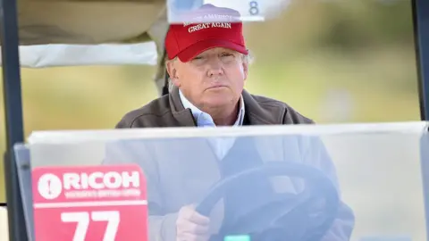Getty Images Donald Trump sits behind the wheel of a golf cart.