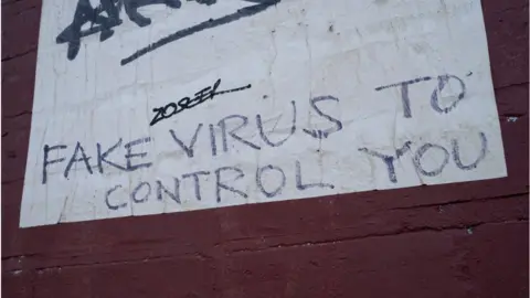 Mike Kemp / Getty Images Graffiti saying "fake virus controls you"