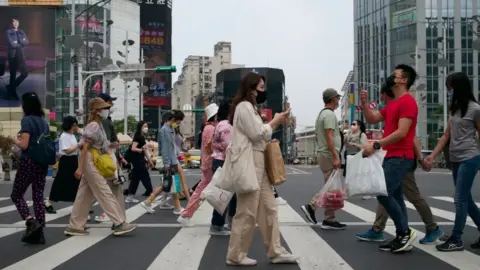 Getty Images This picture taken on April 14, 2023 shows people walking down a street at the Ximen district in Taipei