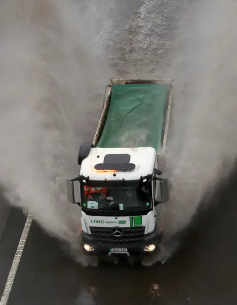 PA Media A lorry passes through a flooded road in Folkestone, Kent, on 14 January 2021