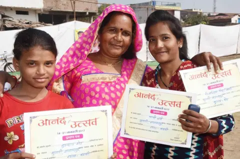 Prakash Hatvalne A woman and two girls show the certificates they received on "happiness day"