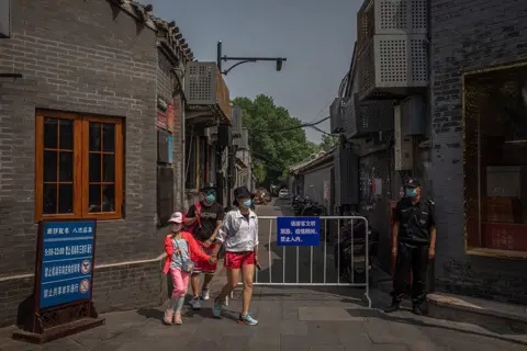 Roman Pilipey / EPA-EFE A family wearing masks in Beijing