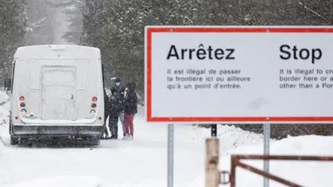 Reuters People board a bus near a sign that says crossings are illegal