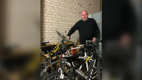 The Beacon Mark Powell standing next to bikes