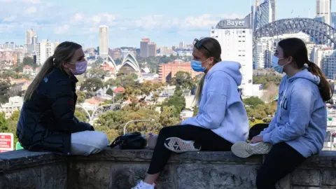 Getty Images Three girls wearing face masks sit above the Bradfield Highway in the suburb of Sydney, Australia. Photo: 7 July 2021