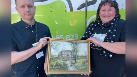 Derian House Tony Smalley hands the painting to Jayne Allman