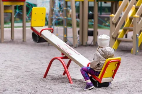 Getty Images A girl sits at one end of a seesaw