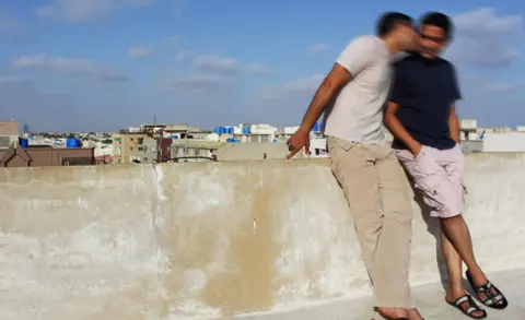 Two men kissing on rooftop