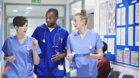 Getty Images 3 nhs nurses walking down corridor