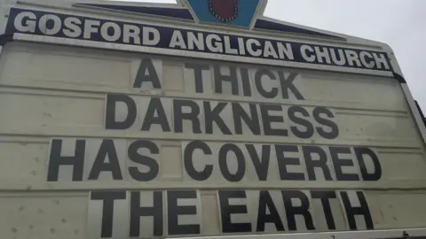 ROD BOWER Gosford Anglican Church billboard reads: "A thick darkness has covered the earth"