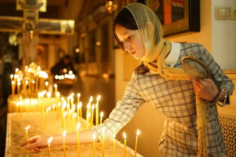 Semyon Antonov / TASS / Getty Images An Orthodox believer lights a candle during a Christmas liturgy