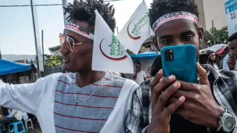 Getty Images A man taking a picture on the eve of the Irreechaa in Bishoftu, south of Addis Ababa, on October 2, 2021.