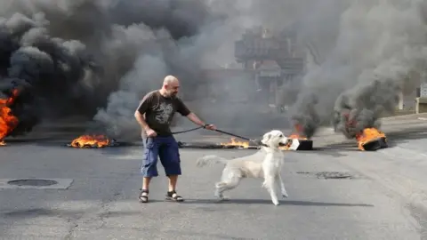 Reuters A protester and his dog stand in front of flames