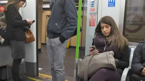 Getty Images Commuters on mobiles