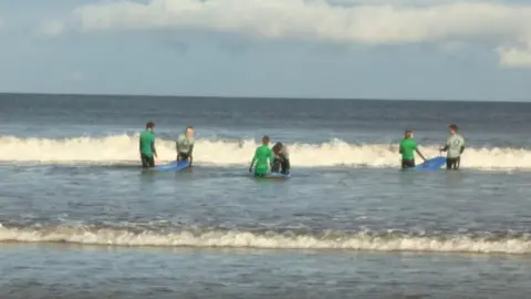 surfing students with their mentors in the sea