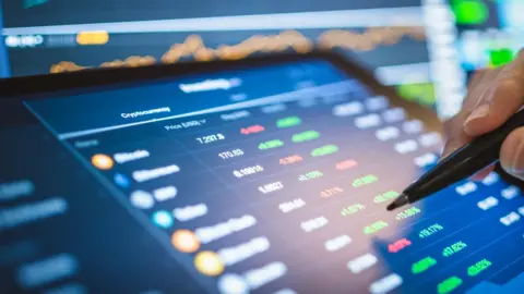 Getty Images A person monitoring the price of various crypto-currencies on a tablet