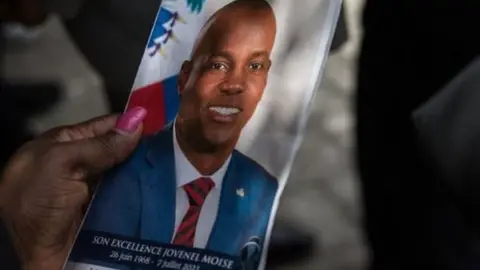 A guest holds a picture of late Haitian President Jovenel Moise during a ceremony at the National Pantheon Museum in Port-au-Prince