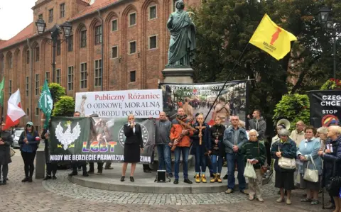 A small counter march in Torun assembled beneath a statue of Copernicus