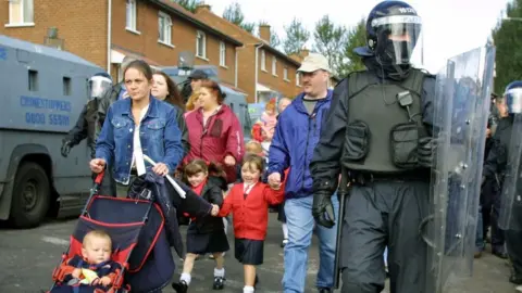 Getty Images/ADRIAN DENNIS Police in riot gear protected families from attack on the school run