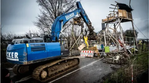 Bernd Lauter/Getty Images A digger destroys a wooden structure on January 2, 2023 in Luetzerath, Germany.