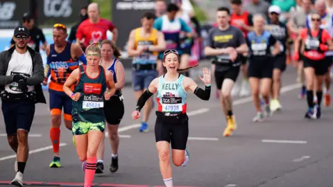 PA Media A woman waves at start of race