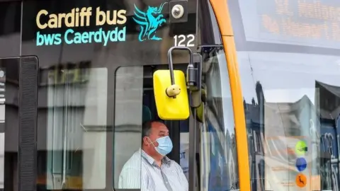 PA Media A bus driver in Cardiff wearing a face mask